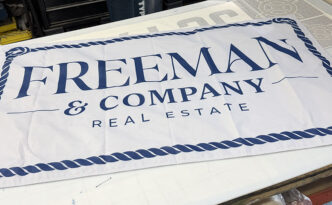 Custom 3 x 5 foot Freeman & Company Real Estate business flag with navy nautical rope border, designed and printed for Long Beach Island, New Jersey