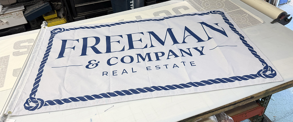Custom 3 x 5 foot Freeman & Company Real Estate business flag with navy nautical rope border, designed and printed for Long Beach Island, New Jersey