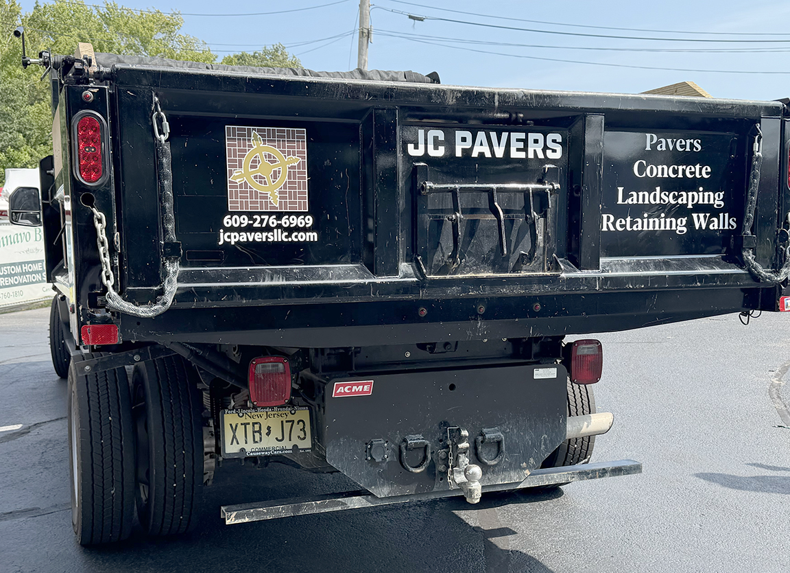 Rear of JC Pavers dump truck with custom fleet branding, logo, phone number, website and paving, concrete, landscaping and retaining wall services