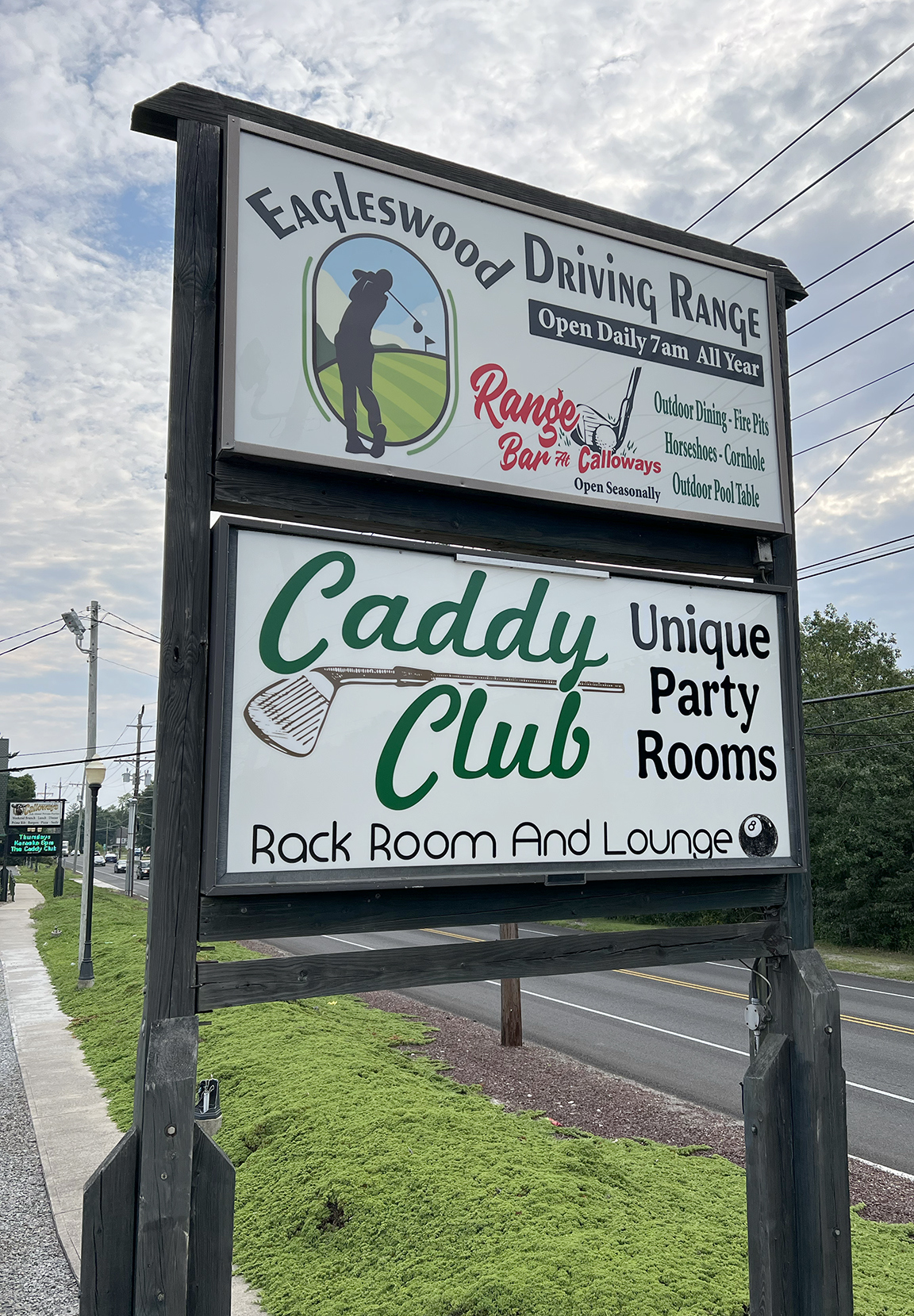 Daytime view of serviced double-panel roadside sign for Eagleswood Driving Range and Caddy Club in West Creek NJ
