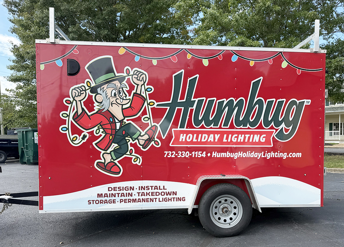 Full driver-side trailer wrap for Humbug Holiday Lighting featuring bold red branding, Christmas light graphics and service information in Ocean County, New Jersey