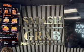Smash N Grab restaurant interior in Manahawkin NJ featuring a raised polished gold dimensional logo, digital menu board and custom LED neon signage